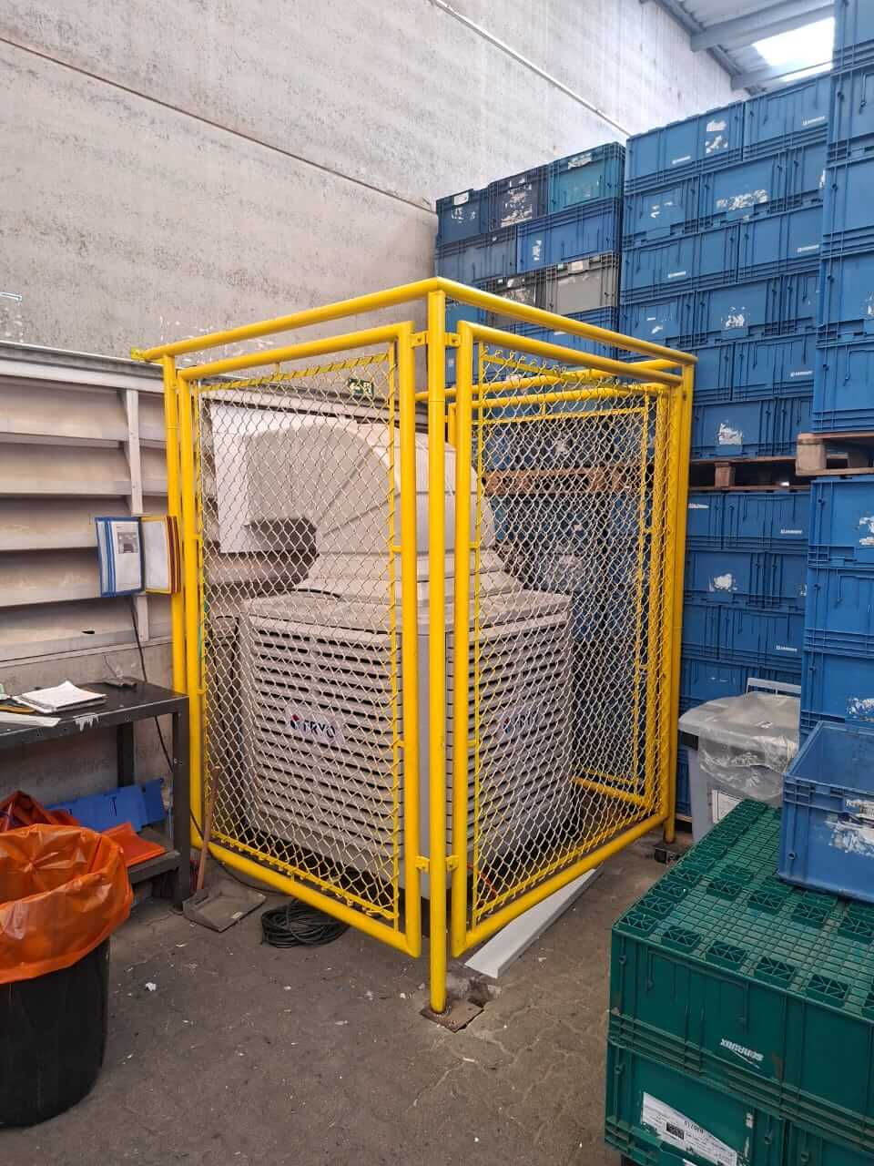 Climatizador industrial com proteção de grade amarela, ideal para ambientes de armazenamento e fábri.