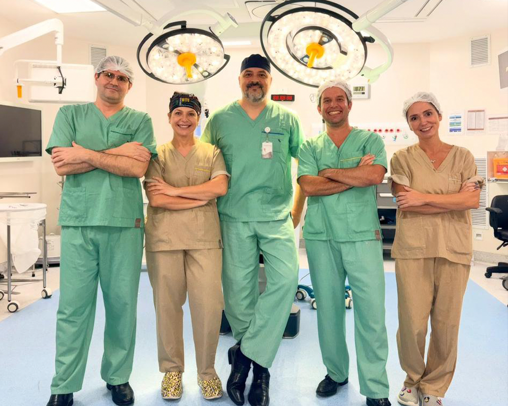 Equipe de profissionais de saúde em sala de cirurgia com equipamentos médicos modernos e iluminação.